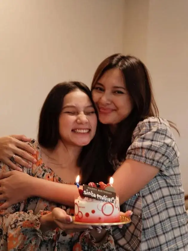 Happy birthday wishes for sister featuring an older sister receiving a loving birthday hug from her younger sister.